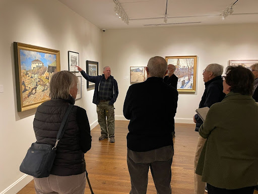 Exhibition Programs A group stands in a gallery, following a tour guide explain a painting.